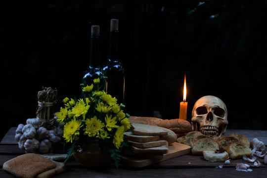 skull with candle put on table have rotten bread around  