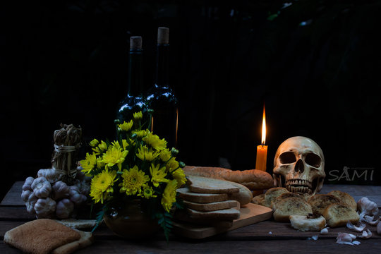 skull with candle put on table have rotten bread around  