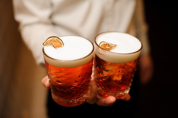 Red cocktail with sweet foam and fresh lime in bartenders hands