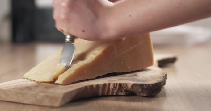 slide of female hand cutting hard parmesan cheese