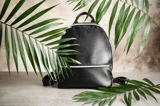 Black leather backpack with palm leaves on light background