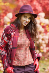 Woman in coat with hat and scarf in autumn park