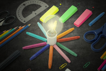 Bright bulb with stationery on the blackboard