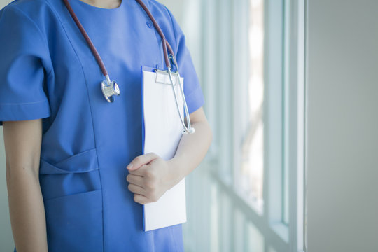 Soft focus Asian medical female doctor or nurse holding patient medical chart in hospital with copyspace and blurred background.