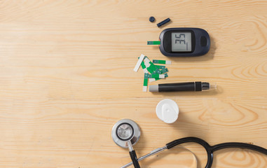 Glucometer set  For Blood Glucose Testing, Syringe for inject  and stethoscope on the wooden table.