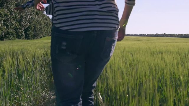 Happy woman and man running through the field with green grass fave fun enjoy freedom nature and summer landscape outdoors. Near runs dog. Slow motion rear back view.