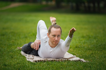 Fototapeta premium Hipster man - yoga instructor performs flexibility exercises in park