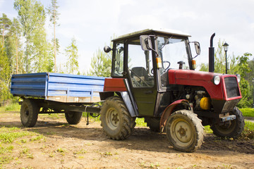 Obraz premium Old red tractor with a trailer on a forest road