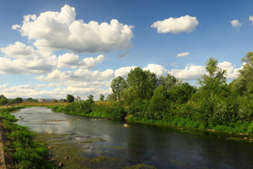 Fototapeta na wymiar river below summer clouds