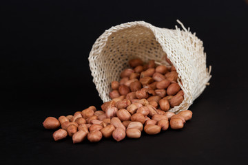 ground nut out of basket on black background