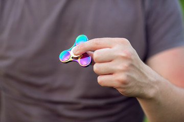 Rainbow hand fidget spinner in the man's hand