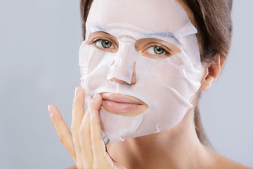 Woman with a cloth moisturizing mask on her face