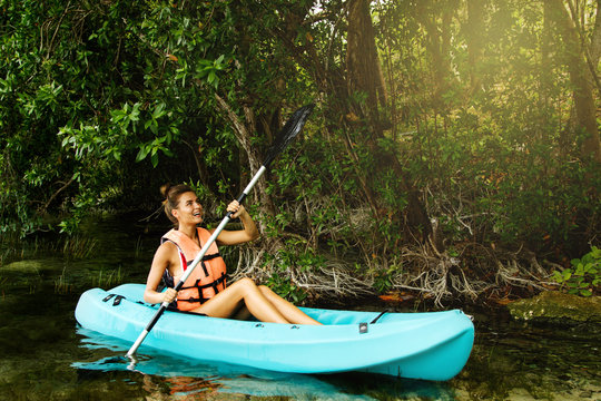 Happy young woman kayaking on the lake