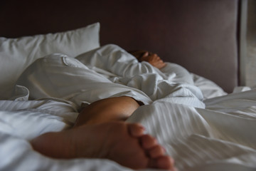 woman laying in bed covering head