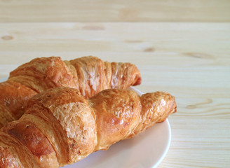 Closed up fresh baked whole wheat croissant pastries served on wooden table, with free space for text and design 