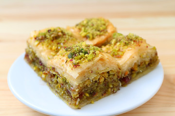 Closed up of Baklava with Pistachio Nuts Served on White Plate, Blurred Background 