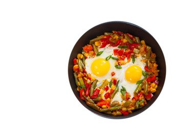 fried eggs with mixed vegetables in a frying pan. top view. isolated on white