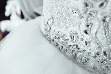 Part of white bridal dress with shining rhinestones. The waist of the bride. Wedding bodice. Close-up - 166033629