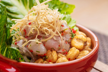 Fresh salad with lupini beans and raw fish served with lettuce leaf in bowl.