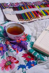 Top view of paint, a blank sheet of paper, cup of tea, markers.