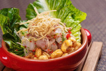 Fresh salad with lupini beans and raw fish served with lettuce leaf in bowl.