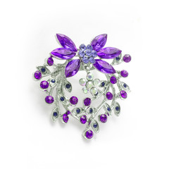 Silver flower brooch with purple diamonds isolated on white