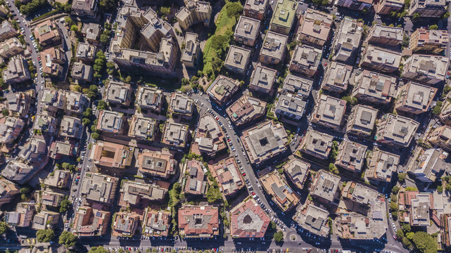 Vista aerea ortogonale di una parte del quartiere Monteverde a Roma. Tra le strade strette e i palazzi si vedono alberi e tanto verde mentre sugli edifici antenne e parabole.