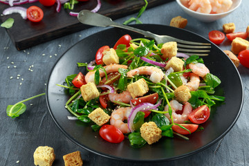 Fresh Healthy Prawns salad with tomatoes, red onion on black plate. concept healthy food
