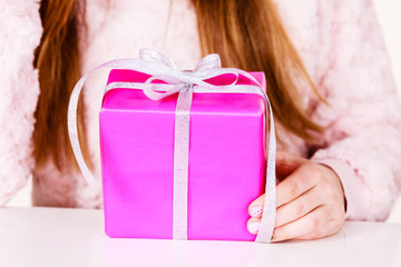 Female hands holding pink gift box with ribbon