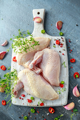 Raw Chicken breast supremes fillets with chilli, pepper corns and thyme on white wooden chopping board