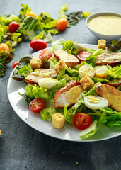 Fresh healthy Caesar salad with chicken, egg quail, tomatoes, Cheese and Croutons in a white plate