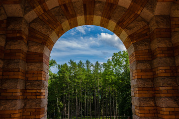 looking through arches out at trees and a bright blue sky