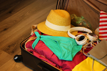Collected suitcase for travel. Suitcase in open view closeup with things to rest on a wooden background