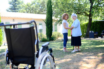 cheerful mature woman visiting her mother elderly senior female walk in retirement house hospital garden