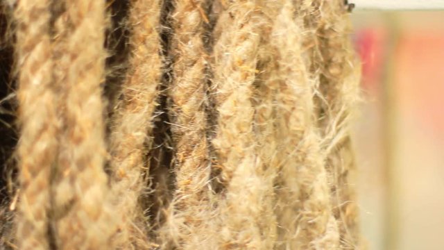 Rope made from flax. Close up of flax texture. Beige flax ropes at flax factory. Old rope from natural material. Ropes hanging vertically at manufacturing line