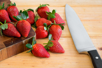 Freshly picked organic strawberries on chopping board with knife.
