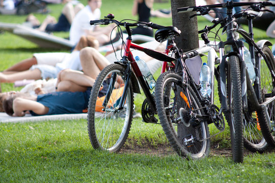 People are resting lying on the lawn in the park after a trip on bicycles