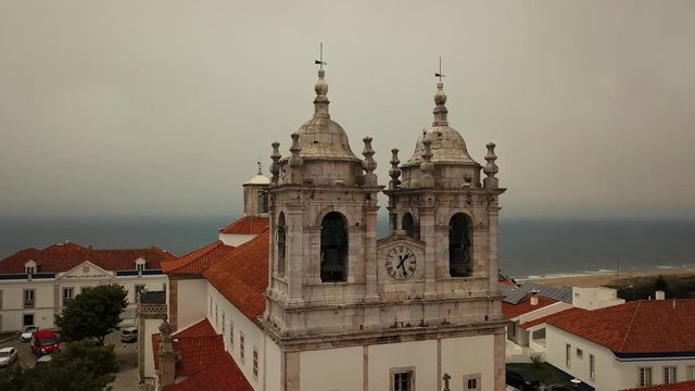 Flight on a drone over Nossa Senhora da Nazare, sanctuary and sandy beach in Portugal
