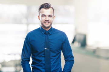 Handsome stylish young man in shirt looking at the camera. Office worker. Business decisions. Beautiful light background