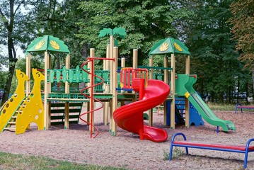 цветная детская площадка в парке с деревьями