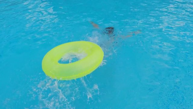 The girl dives into the water. The girl dives into the inflatable circle.