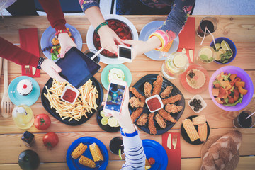 Top view of group of people having dinner together while sitting at wooden table. Food on the table. People eat fast food. Photograph food