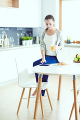 Fototapeta premium Young woman with orange juice and tablet in kitchen.