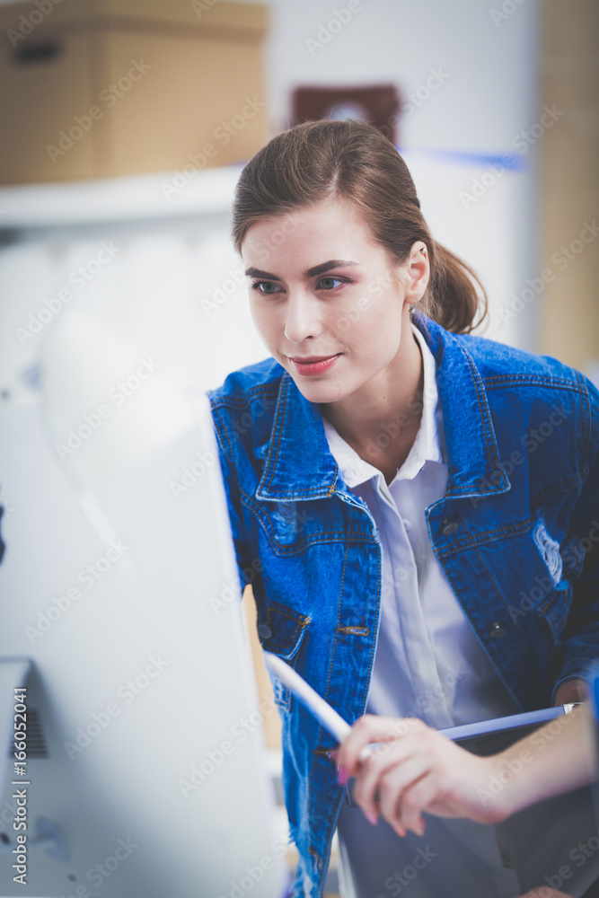 Wall mural two young woman standing near desk with instruments, plan and laptop.