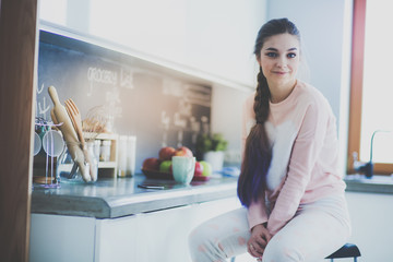 Young woman sitting on table in the kitchen.