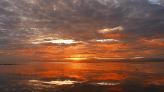 A very red, colorful sunrise video from Dumaguete City shores, with mirror like ocean. Presented in real time.