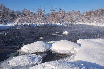 River Koksha surrounded by trees under hoarfrost and snow in Altai region in winter season
