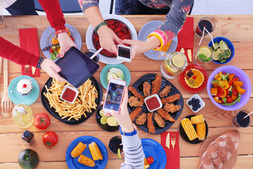 Top view of group of people having dinner together while sitting at wooden table. Food on the table. People eat fast food. Photograph food