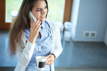 happy woman drinking tea in the kitchen at home and talking on the phone. Woman in the kitchen.