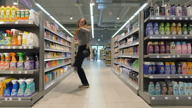 Young woman dancing through grocery store aisles. 